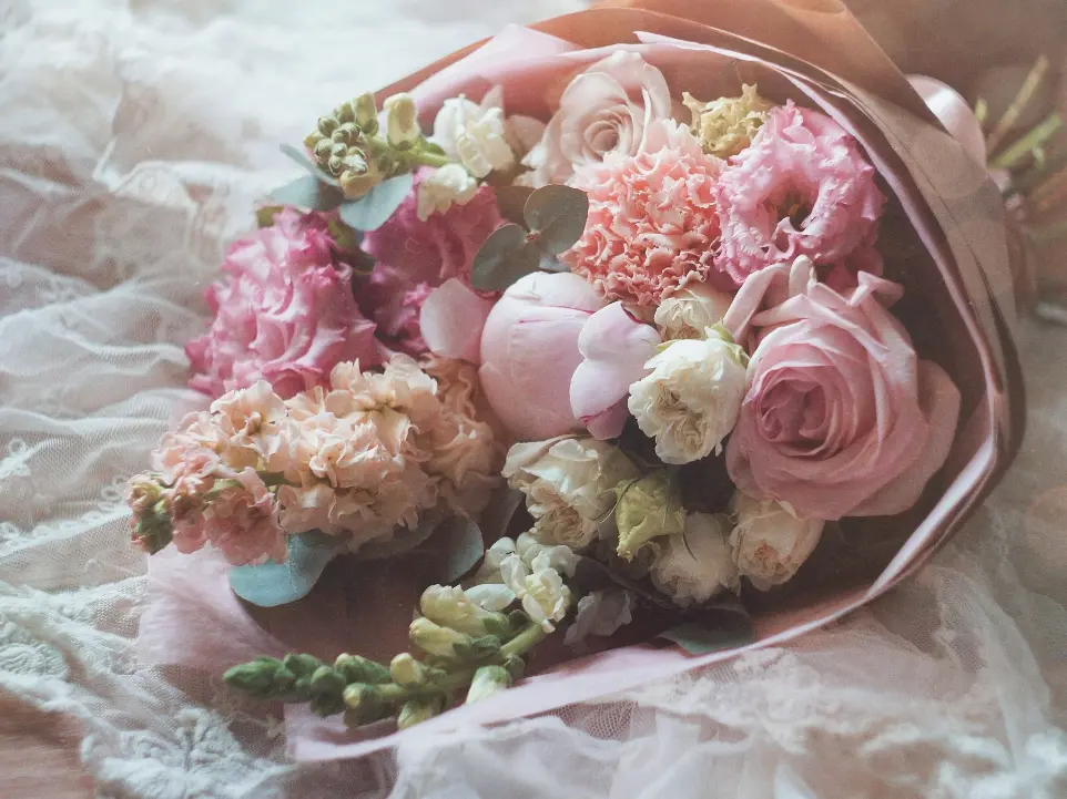 a bouquet of pink and white flowers laying on a lace covered surface